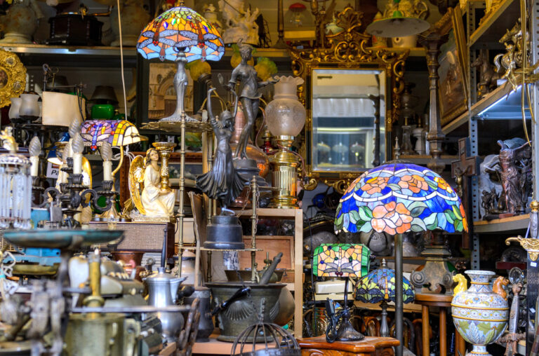 Boutique d'antiquités remplie de lampes Tiffany colorées, statues, miroirs dorés et objets anciens variés.