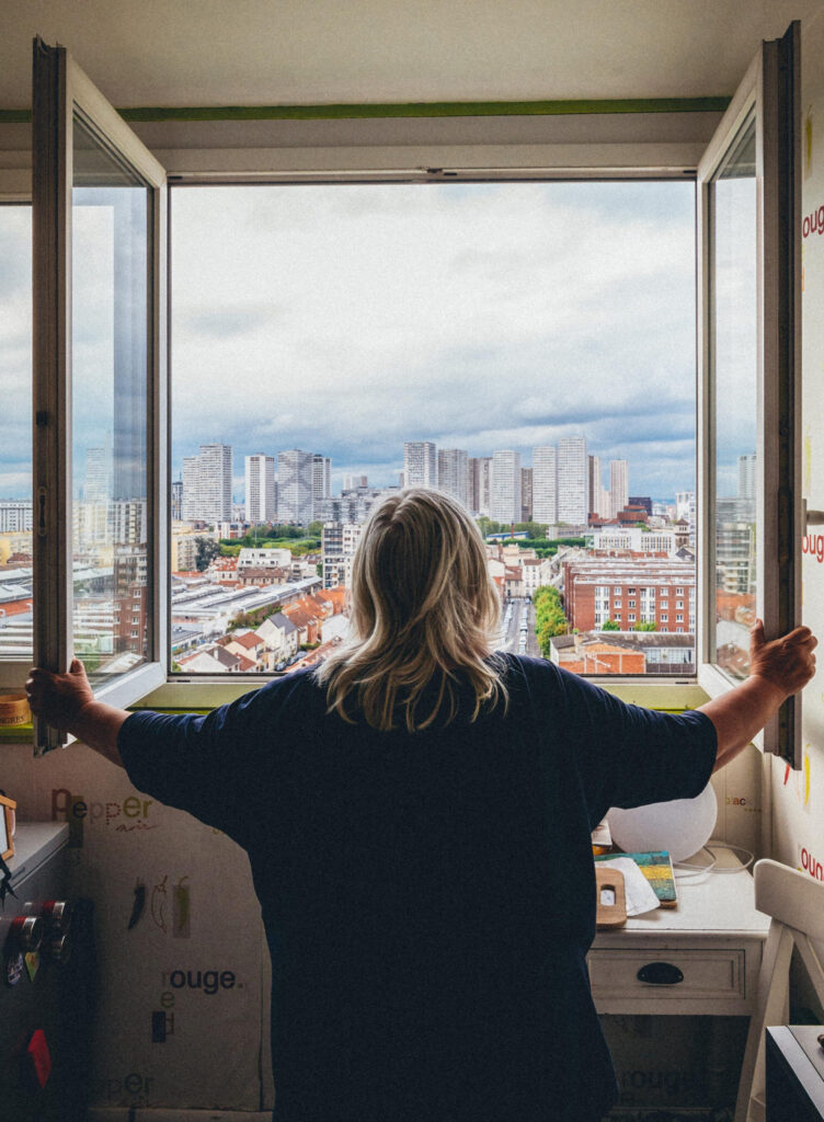 Photo d'une personne âgée ouvrant les fenêtres de son appartement de quartier populaire