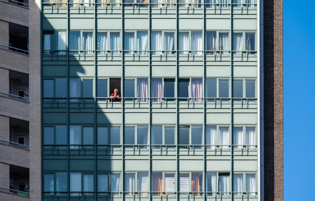 Photo d'un immeuble de quartier populaire avec une personne âgée à sa fenêtre